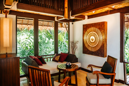 MAY 22, 2014 Krabi, THAILAND - Asian luxury style hotel living room with contemporary wooden furnitures, chairs, tables , pillows and Thai style wall decorationのeditorial素材