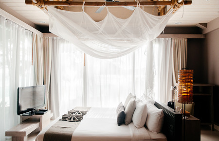 MAY 21, 2014 Krabi, THAILAND - Asian Thai tropical luxury resort room with wooden bed and white curtain and bamboo floor lamps. High ceiling hotel room interior.のeditorial素材