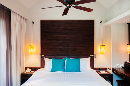MAY 21, 2014 Krabi, THAILAND - Asian Thai tropical luxury resort room with wooden bed and white curtain, pedant lamps and ceiling fan. Contemporary hotel room interior.のeditorial素材