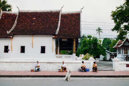 APR 4, 2019 Luang Prabang, Laos - Senior local people and dog waiting for Buddhist Monk in Traditional morning Alms  ceremony in front of old templeのeditorial素材