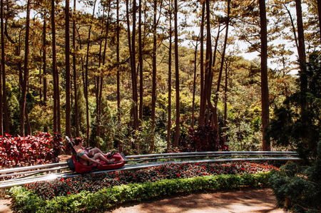 FEB 26, 2014 Dalat, Vietnam - Tourist couple enjoy downhill roller coaster trolley passing through tropical forest to  Datanla waterfall. Famous tourist activity outside city.のeditorial素材