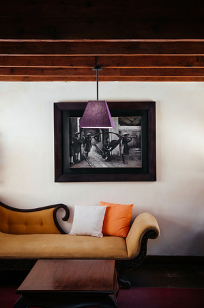 FEB 25, 2014 Dalat, Vietnam - Vintage colonial tropical country house living room hard wood floor classic sofa couch, pedant lamps and old picture frame on white wallのeditorial素材