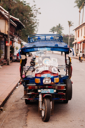 APR 4, 2019 Luang Prabang, Laos - Tuk Tuk Skylab and French Colonial building on main street - Famous transport type among touristのeditorial素材