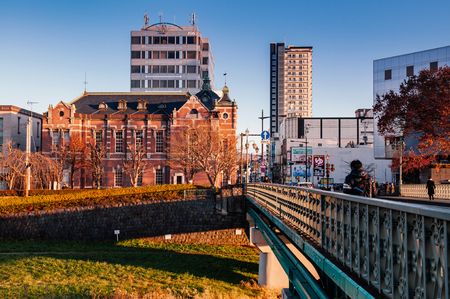 DEC 2, 2018 Iwate, Japan - Red brick building classic old Bank of Iwate in Morioka city at evening with sunset light. Iconic land mark with people walk on Nakanohachi bridge - Tohoku region beautiful landscapeのeditorial素材