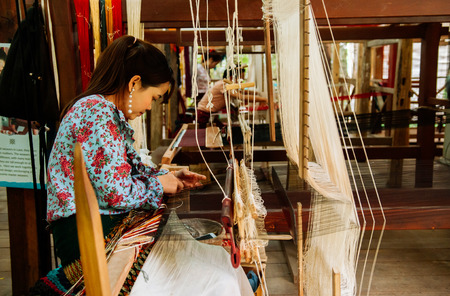 APR 4, 2018 Luang Prabang, Laos - Young woman working on Vintage Laos style wooden weaving loom with silk fiber, handicraft work, weaving tool. Culture tourism at Ock Pop Tok handicraft centerのeditorial素材