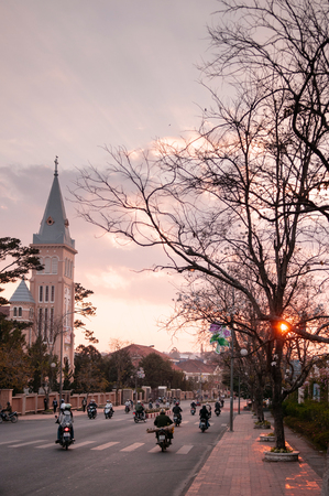 FEB 26, 2014 Dalat, Vietnam - Warm sunset light and Motorcycle traffic in evening at Da Lat Cathedral with Purple orchid treeのeditorial素材