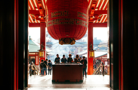 NOV 29, 2018 Tokyo, Japan - Japanese praying at Asakusa Sensoji temple under giant red lantern seen from inside main hall. Tokyo most famous religious related attractionのeditorial素材