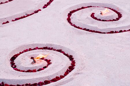 Romantic beach flower and candle setting for honeymoon dinner close up sand detail - Evening summer...