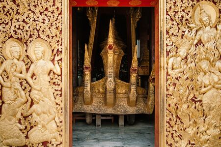 Luang Prabang, Laos - Ancient Golden Royal carriage and casket Royal Funeral Urn behind mural carved wood wall at Wat  Xieng thong museum.  Most Famous tourist attractionのeditorial素材