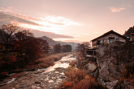 Yamagata, Japan - DECEMBER 3, 2018 : Old Japanese house on rock cliff by Tachiya river with evening sunset light and warm tone sky in late autumnのeditorial素材