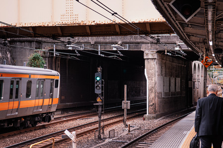 Tokyo, Japan - DECEMBER 5, 2018 : Tokyo JR Chuo line train leaving station platform at Ichigaya station with passenger walking seen from behindのeditorial素材