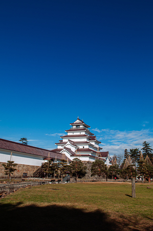 DEC 4, 2018 Aizu Wakamatsu, JAPAN - Aizu Wakamatsu Tsuruga Castle and pine tree in park under winter blue sky. Fukushima Samurai lord fortess in Edo periodのeditorial素材