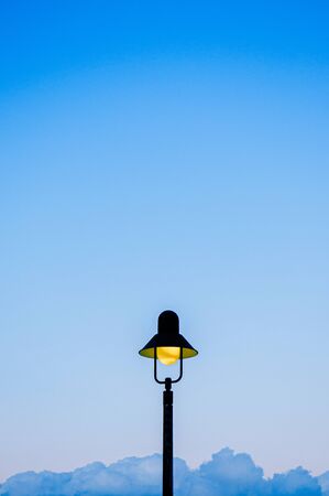 Vintage retro electric light pole with blue evening sky background with copy space for design work. Vertical imageの写真素材