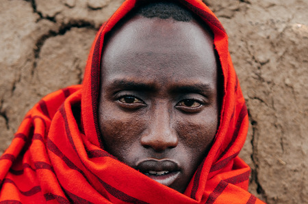 JUN 24, 2011 Serengeti, Tanzania - Portrait of African Masai or Maasai tribe man in red cloth eyes staring at camera. Clearly face detail wrinkle and skin. Ethnic group of Ngorongoro Consevation, Serengeti Savanna forest.のeditorial素材