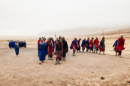 JUN 24, 2011 Serengeti, Tanzania - Group of African Masai or Maasai tribe  in red and blue cloth dancing on dusty ground in village. Ethnic group of Ngorongoro Consevation, Serengeti Savanna forest.のeditorial素材