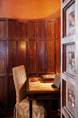JUN 23, 2011 Ngorongoro, Tanzania - Luxury African tribal hut  interior decoration with old vintage wooden colonial table and chair under warm light in wooden wall reading room.のeditorial素材