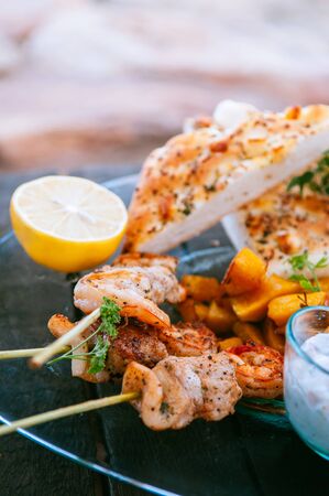 Shrimps and chicken Piri Piri African style Barbecue skewers with flatbread on glass plate close up imageの写真素材