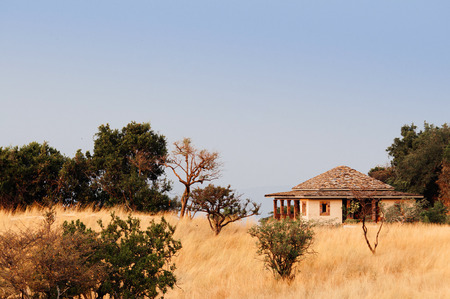 JUN 21, 2011 Serengeti, Tanzania - Serengeti Grumeti Reserve wildlife park luxury Safari lodge in grass field on beautiful slope of mountain hill under evening warm dramatic lightのeditorial素材
