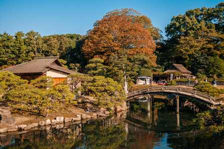 NOV 18, 2014 Okayama, Japan - Old vintage Japanese tea house in Okayama Korakuen park with wooden bridge and pond during autumn seasonのeditorial素材