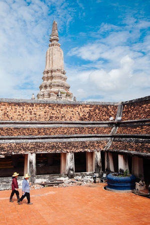 NOV 5, 2014 Ayutthaya, Thailand - Ancient Buddhist pagodas and temple wall of Wat Putthaisawan historic Temple with local people walking.のeditorial素材