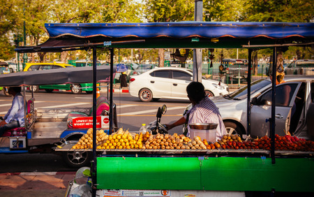 OCT 24, 2019 Bangkok, Thailand - Bangkok street food grill and fry sausage snack stall vender on busy traffic road side with Tuk Tuk taxi in old town areaのeditorial素材