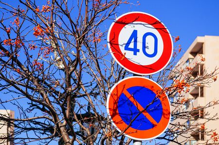 Street traffic speed limit and no enter sign with autumn tree against blue sky background.