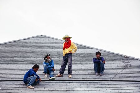 MAY 8, 2010 Bangkok, Thailand - Group of Asian male construction labours sitting on building roof  at building construction site no safety equipmentの写真素材