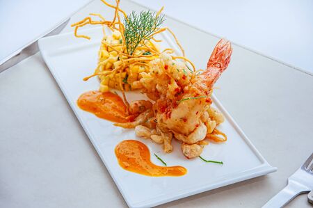 Crispy spicy deep fried tiger prawn with mango salsa and hot chilli thousand island sauce on white plateの写真素材