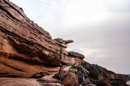 Large Sand stone canyon cliff shoreline of Mekong river under evening lighton cloudy day at Ban Pha...