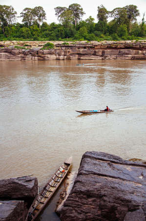 MAY 17, 2010 , Ubon Ratchathani, Thailand - Large Sand stone canyon cliff shoreline of Mekong river and local Thai fishermans boats at Ban Pha Chan.のeditorial素材