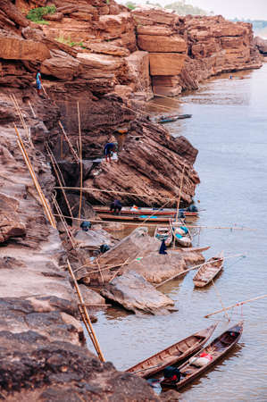 MAY 17, 2010 , Ubon Ratchathani, Thailand - Large Sand stone canyon cliff shoreline of Mekong river and local Thai fishermans at Ban Pha Chan.のeditorial素材