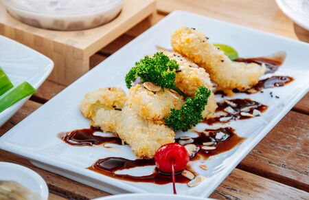 Crispy Fried banana flitter with cherry and chocolate sauce in white plate, Asian style dessert.の写真素材