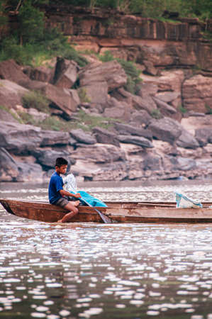MAY 17, 2010 , Ubon Ratchathani, Thailand - Local Young Thai fisherman and fishing net on old wooden boat in Mekong river, simple and charming Southeast Asia rural life of Indochina regionのeditorial素材