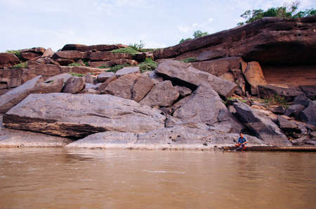 MAY 17, 2010 , Ubon Ratchathani, Thailand - Large Sand stone canyon cliff shoreline of Mekong river and local Thai fishermans at Ban Pha Chan.のeditorial素材