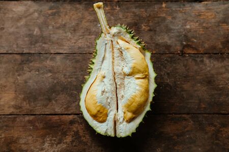 Fresh smelly yellow Durian fruits half cut open on old wood background. King of fruit with spike and unique smellの写真素材