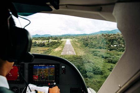 Pilots in the cockpit during a flight with commercial airplane. Landing with runway scene in valley....