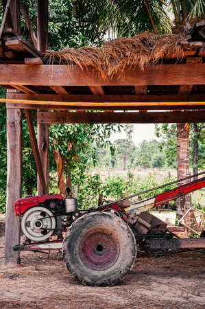 Small agriculture tractor or wheel plough in Asian local farmer house with muddy groundの写真素材