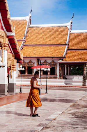 SEP 16, 2012 Sakon Nakhon, Thailand - Buddhist monk with umbrella walking in Wat phra that choeng chum, sacred temple of Sakon Nakhon - Thailandのeditorial素材