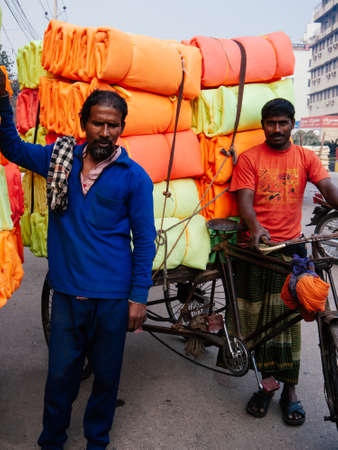 FEB 17, 2012 Dhaka, Bangladesh - Bangladesh waorker people carrying a lot of colourful fabric rolls ...