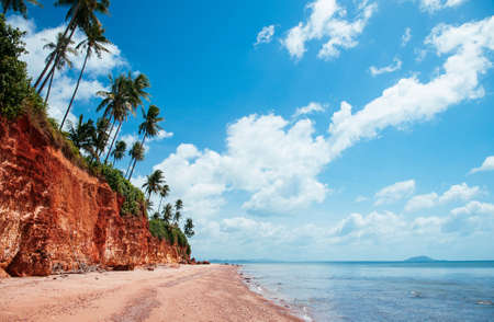 Beautiful tranquil tropical island red cliff  rock beach with blue sky and clouds in summer,...
