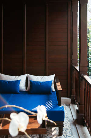 MAR 5, 2012 Chiang Mai, Thailand - Red couch seat on Asian comtemporary patio leisure and resting area with White Phalaenopsis orchid in foregroundのeditorial素材
