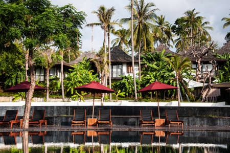 MAY 23, 2010 Phuket, Thailand - Infinity edge pool under blue sky in summer with beach umbrellas in tropical island resort in Phuket.のeditorial素材