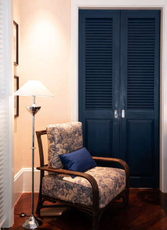 MAR 5, 2012 Chiang Mai, Thailand - Classic rattan chairs furniture in Asian comtemporary bedroom with warm light floor lamp and blue doorのeditorial素材