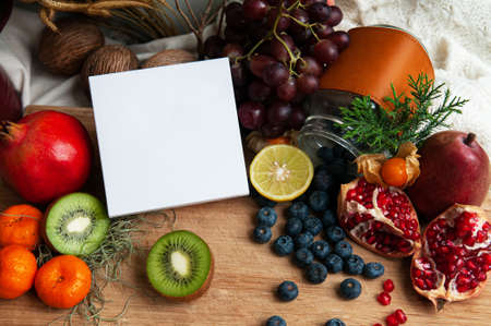 Blank white box packaging among colourful fruits, berries, kiwi, pomegranate and citrus. Dietary supplement packaging box.の写真素材