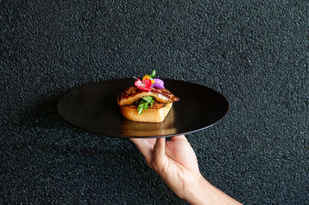 Foie Gras serving with toasted bread and green salad with black dark wall backgroundの写真素材