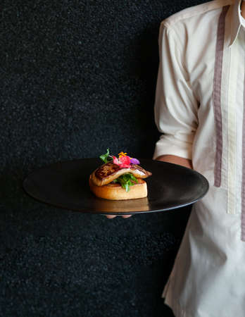 Foie Gras serving with toasted bread and green salad with black dark wall backgroundの写真素材