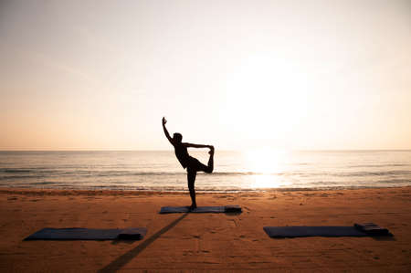 Silhouette Morning Yoga against rising sun on island beachの写真素材
