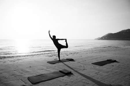 Silhouette Morning Yoga against rising sun on island beachの写真素材