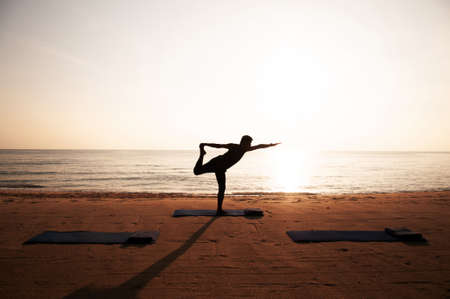 Silhouette Morning Yoga against rising sun on island beachの写真素材