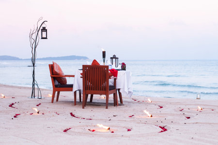 Honeymoon dinner table on island beach with candle at evening in Thailandの写真素材